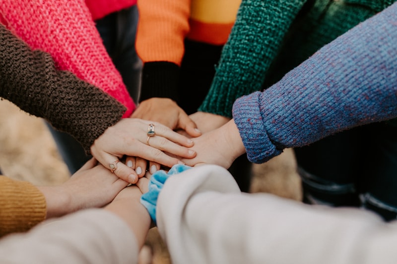 Gruppo diverso che unisce le mani, maglioni colorati